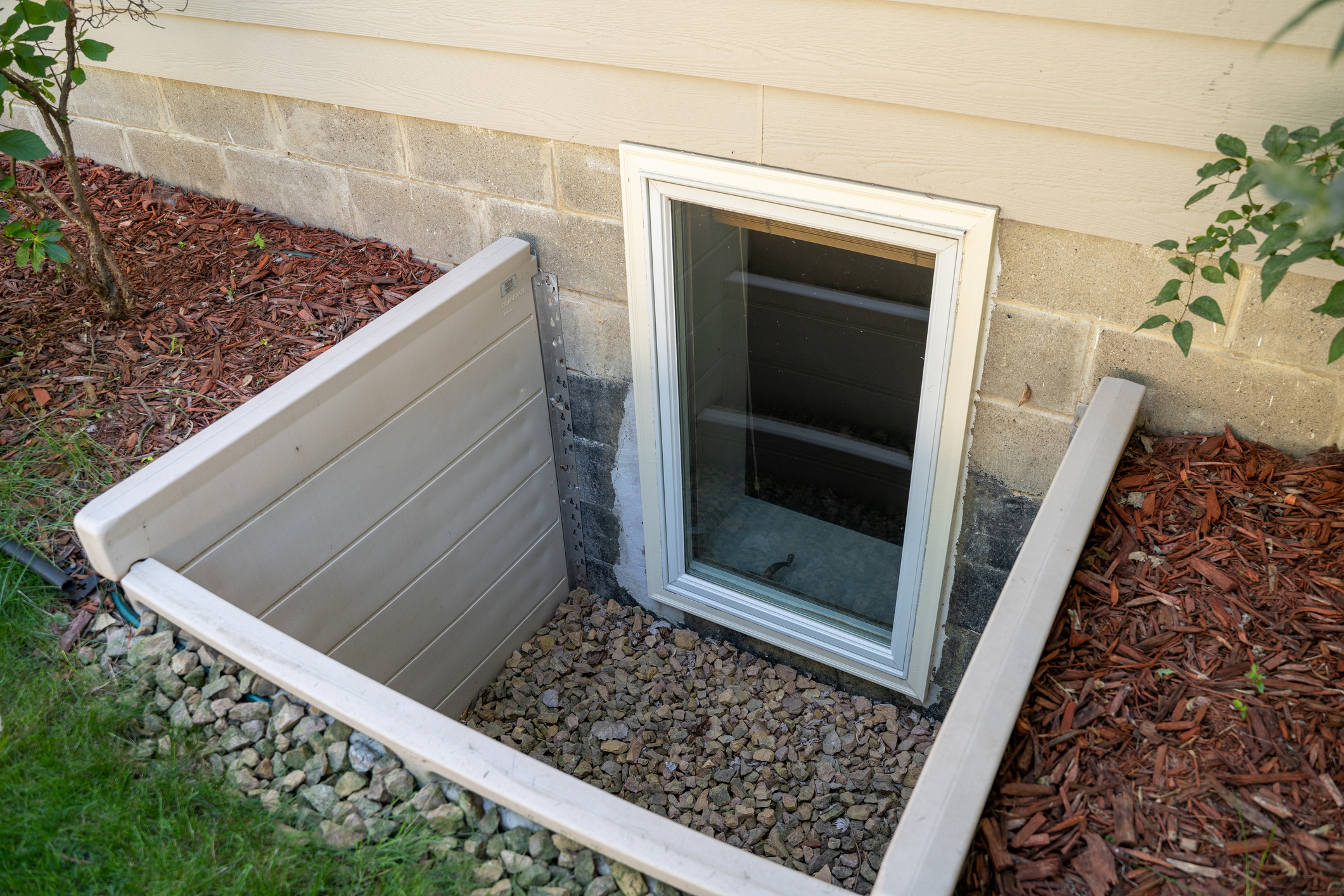 Exterior view of an egress window in a basement bedroom. These windows are required as part of the USA fire code for basement bedrooms Exterior view of an egress window in a basement bedroom. These windows are required as part of the USA fire code for basement bedrooms